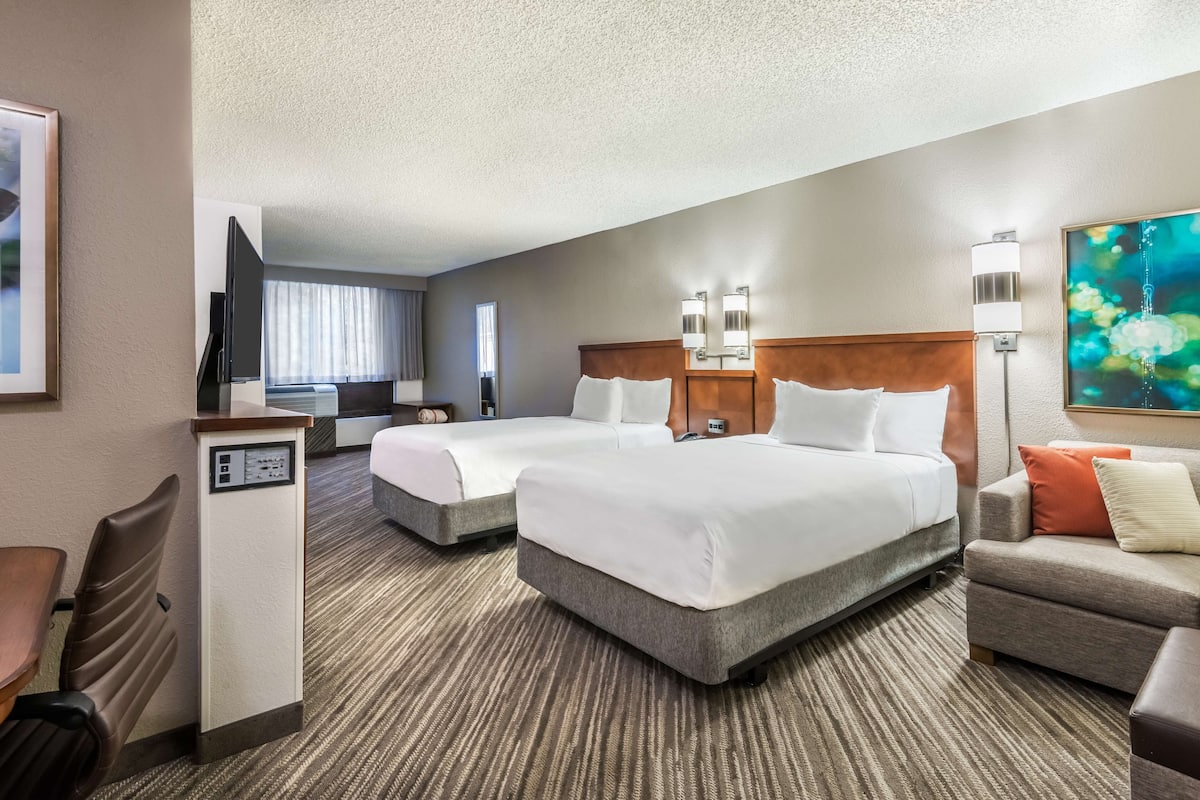 Une chambre d’hôtel avec deux lits, un bureau, une chaise et un canapé.