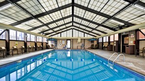 Una piscina interior con techo alto, señalización clara y suelo de baldosas.