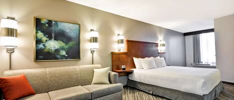 Een hotelkamer met een bed, een bank, een schilderij en wandlampen.
