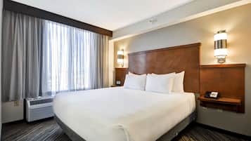 Habitación de hotel con una cama grande, una mesita de noche con teléfono y una lámpara de pared.
