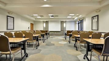A conference room with hexagonal carpet tiles, beige chairs, and tables.