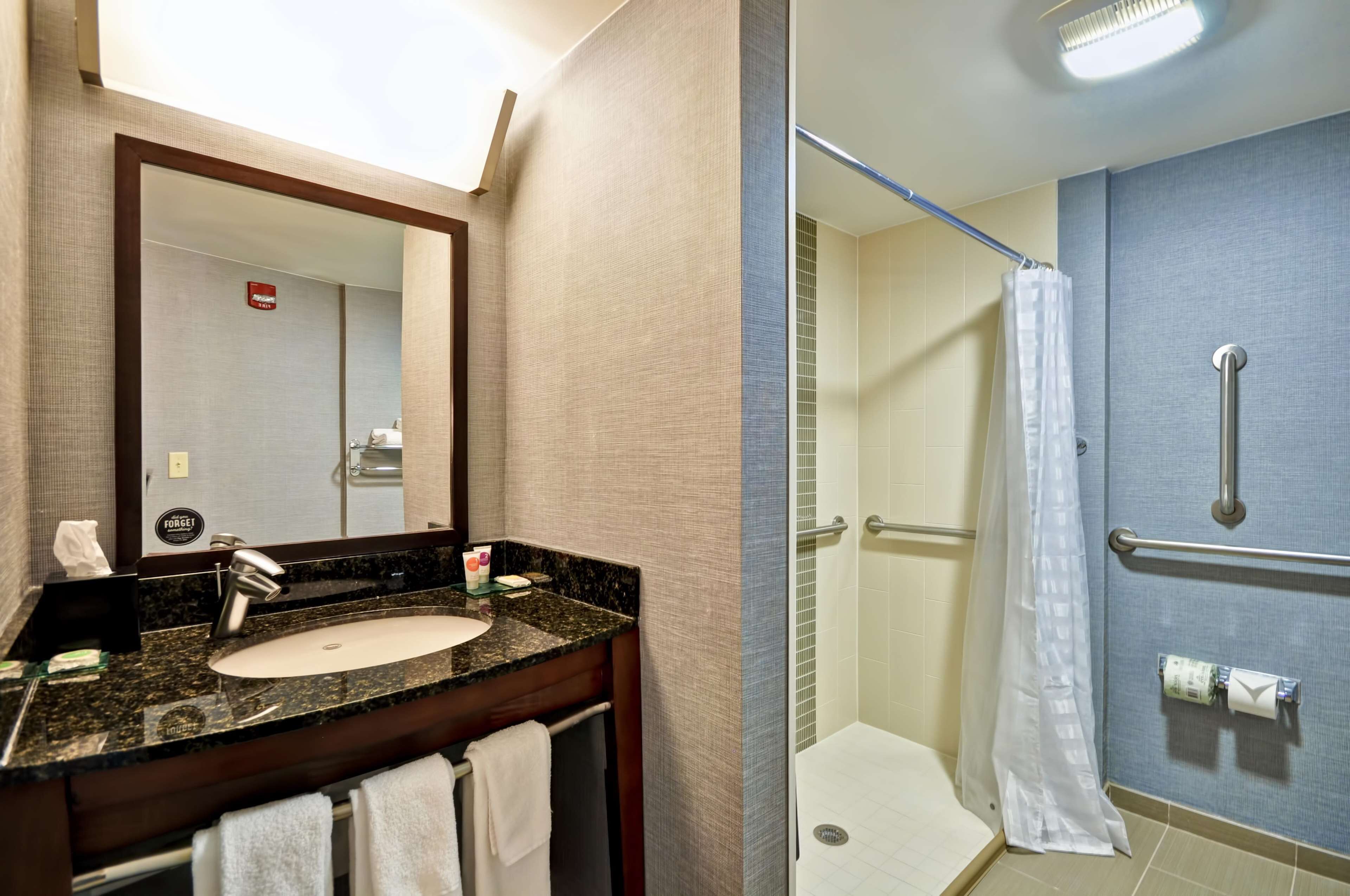 A bathroom with a sink, mirror, and shower.