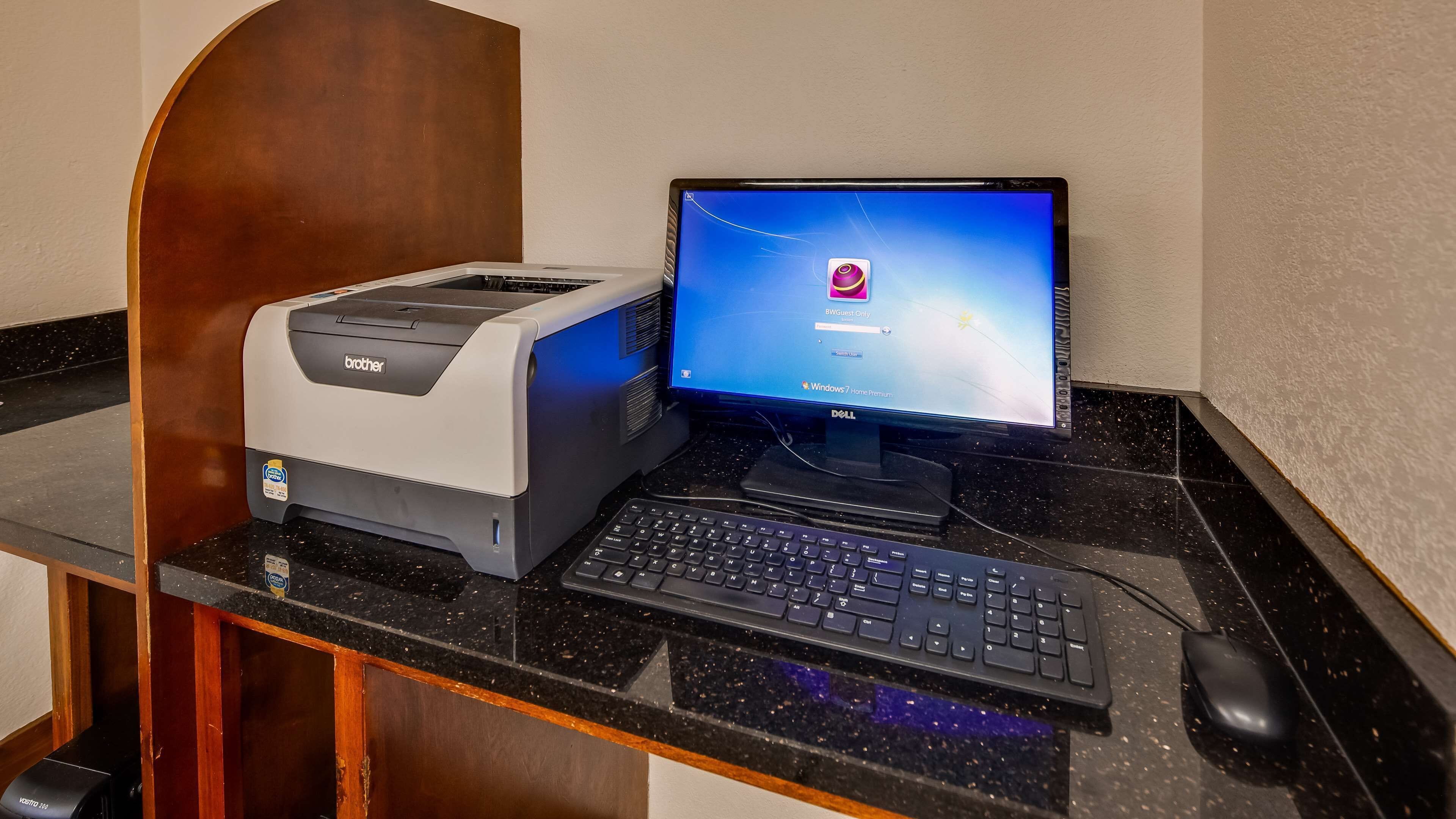 Una computadora de escritorio con una impresora Brother, un teclado y un ratón sobre una encimera negra.