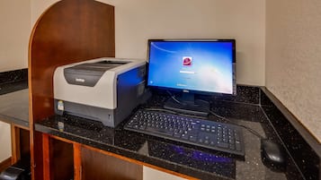 A desktop computer with a Brother printer, a keyboard, and a mouse on a black countertop.
