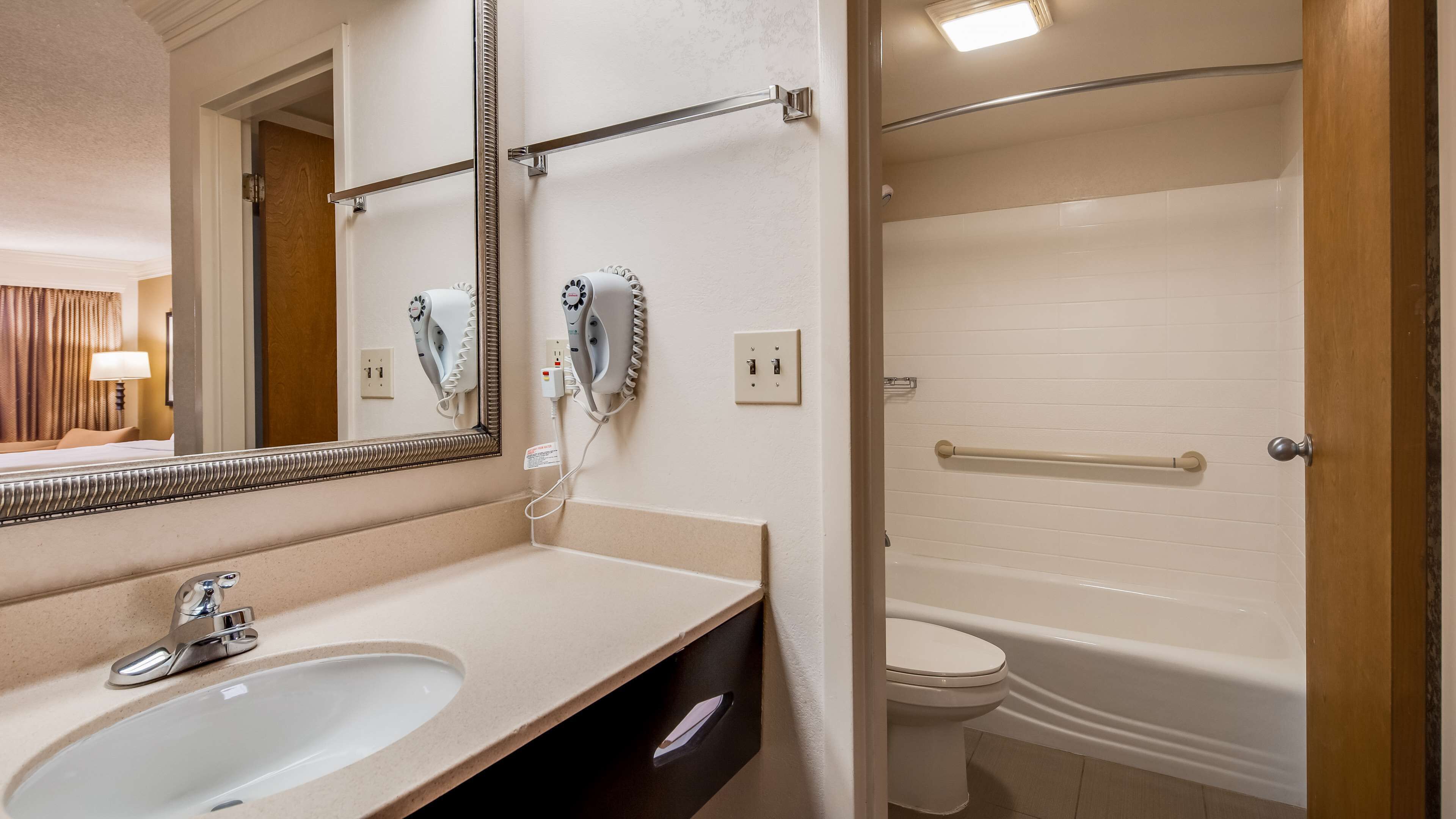 Un baño con lavabo, espejo, secador de pelo y toallero.