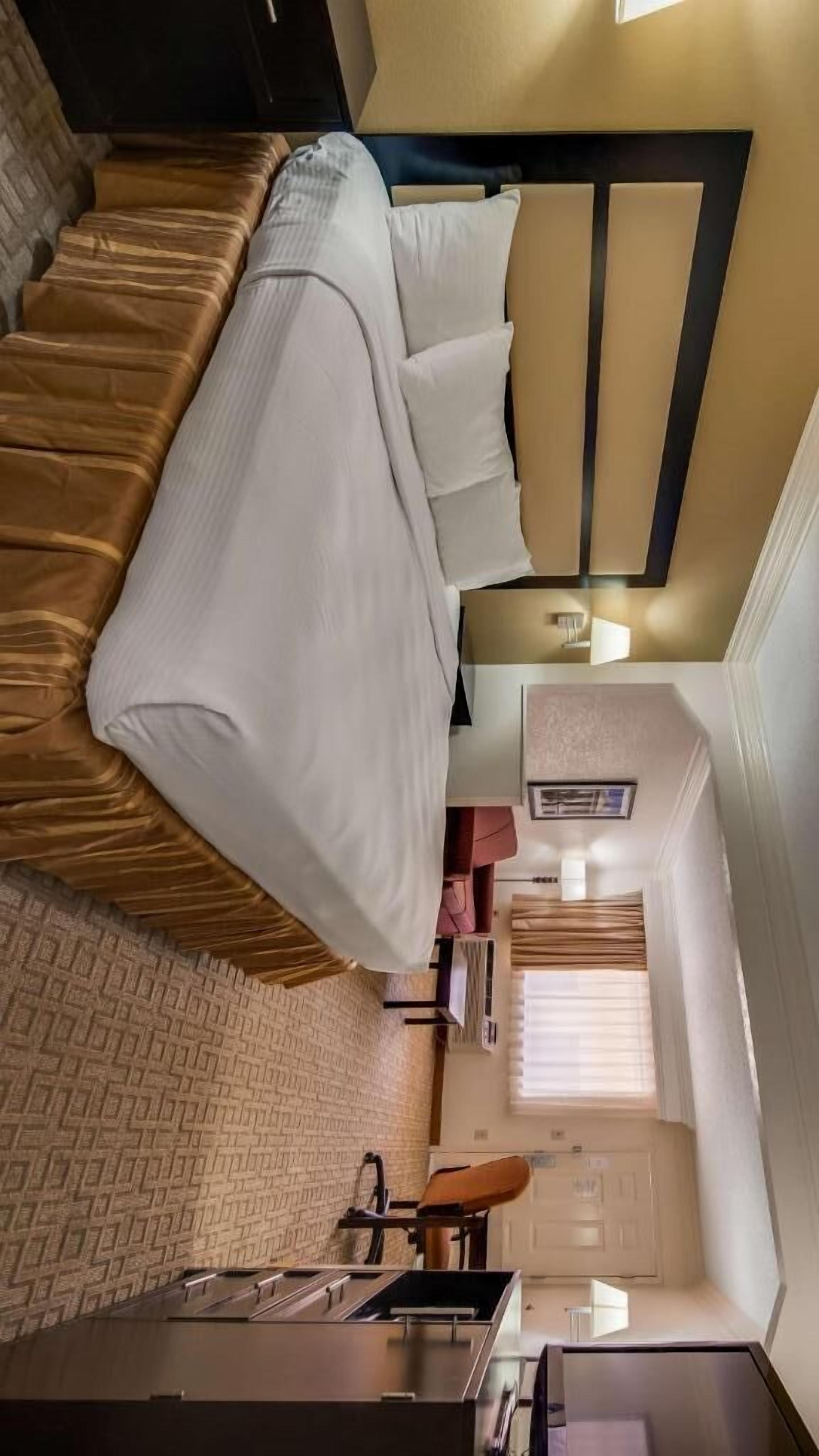 Una habitación de hotel compacta con cama, kitchenette pequeña y baño.