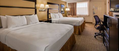A hotel room with two beds, a desk, a chair, a TV, and a window with curtains.