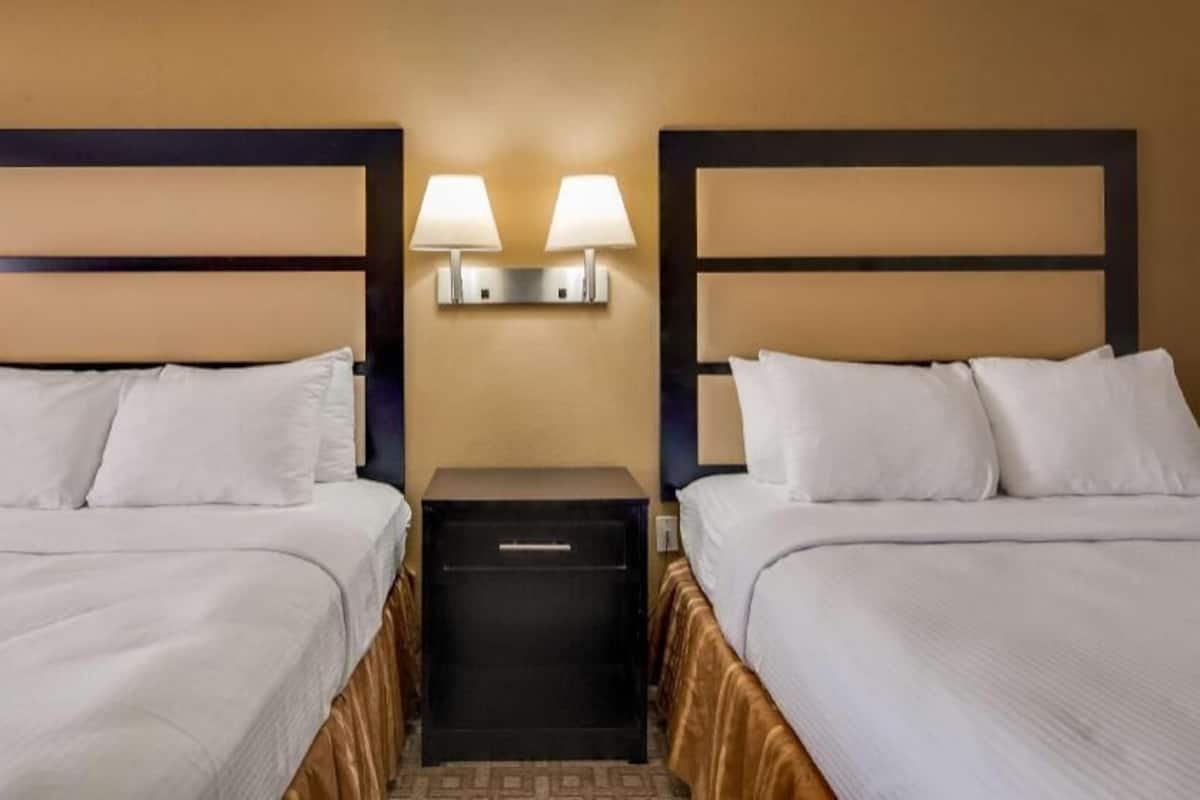 A hotel room with two beds, a nightstand with lamps, and a minibar.