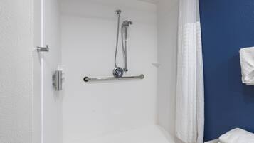 A shower area with a grab bar, a white curtain, and a towel rack.