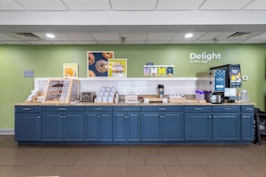 A self-service breakfast station with a variety of food options, a coffee machine, and a refrigerator.