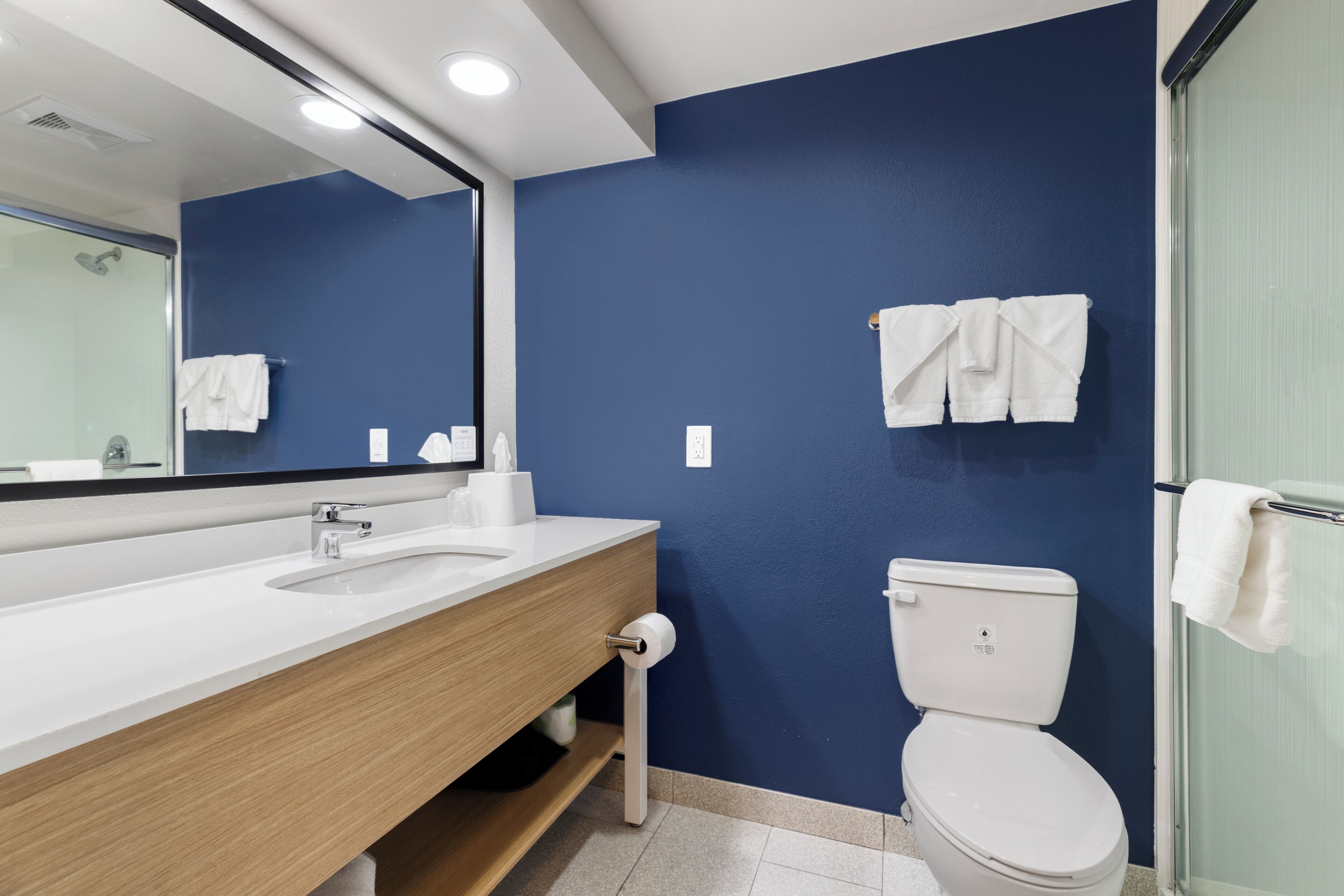 Un baño con un lavabo blanco, un espejo, un inodoro y toallas colgadas en la pared.