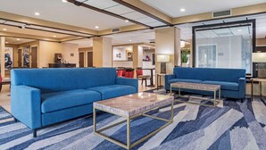 A spacious lobby with two blue sofas, a marble coffee table, and a patterned rug.