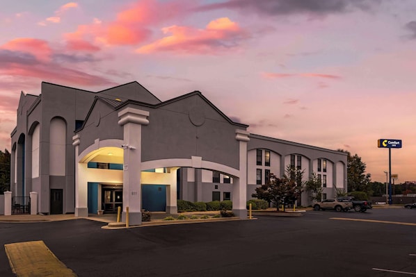 A hotel with a modern architectural design, featuring a prominent entrance with a blue door and a sign indicating it is a Comfort Inn.