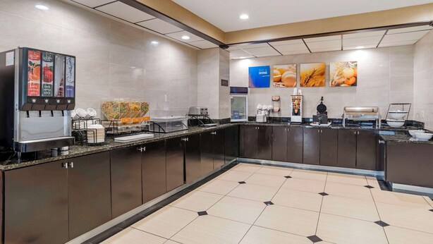 A modern kitchen area with a coffee machine, food display, and a tiled floor.