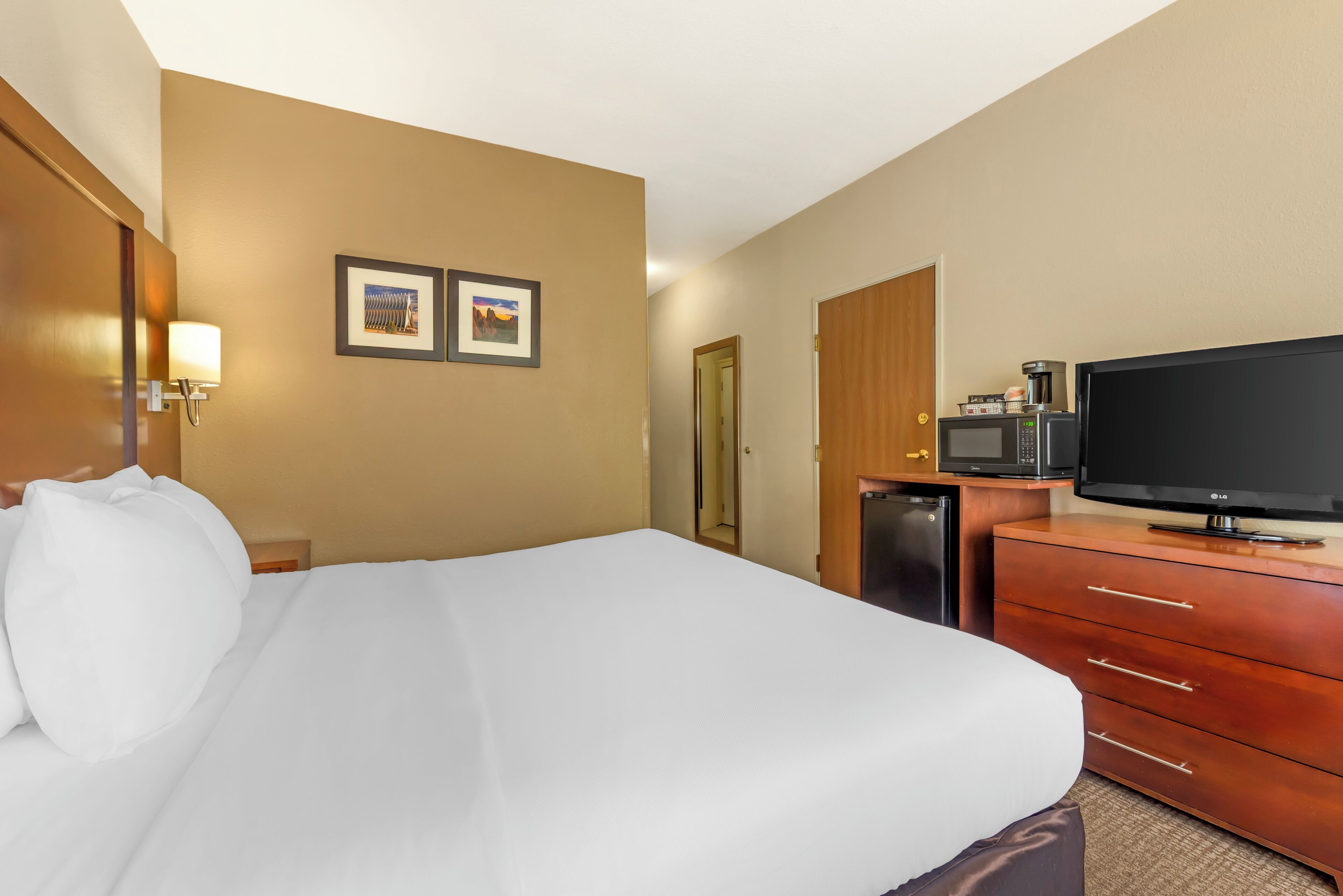 Une chambre d’hôtel avec un grand lit, une télévision, un four à micro-ondes et une machine à café.