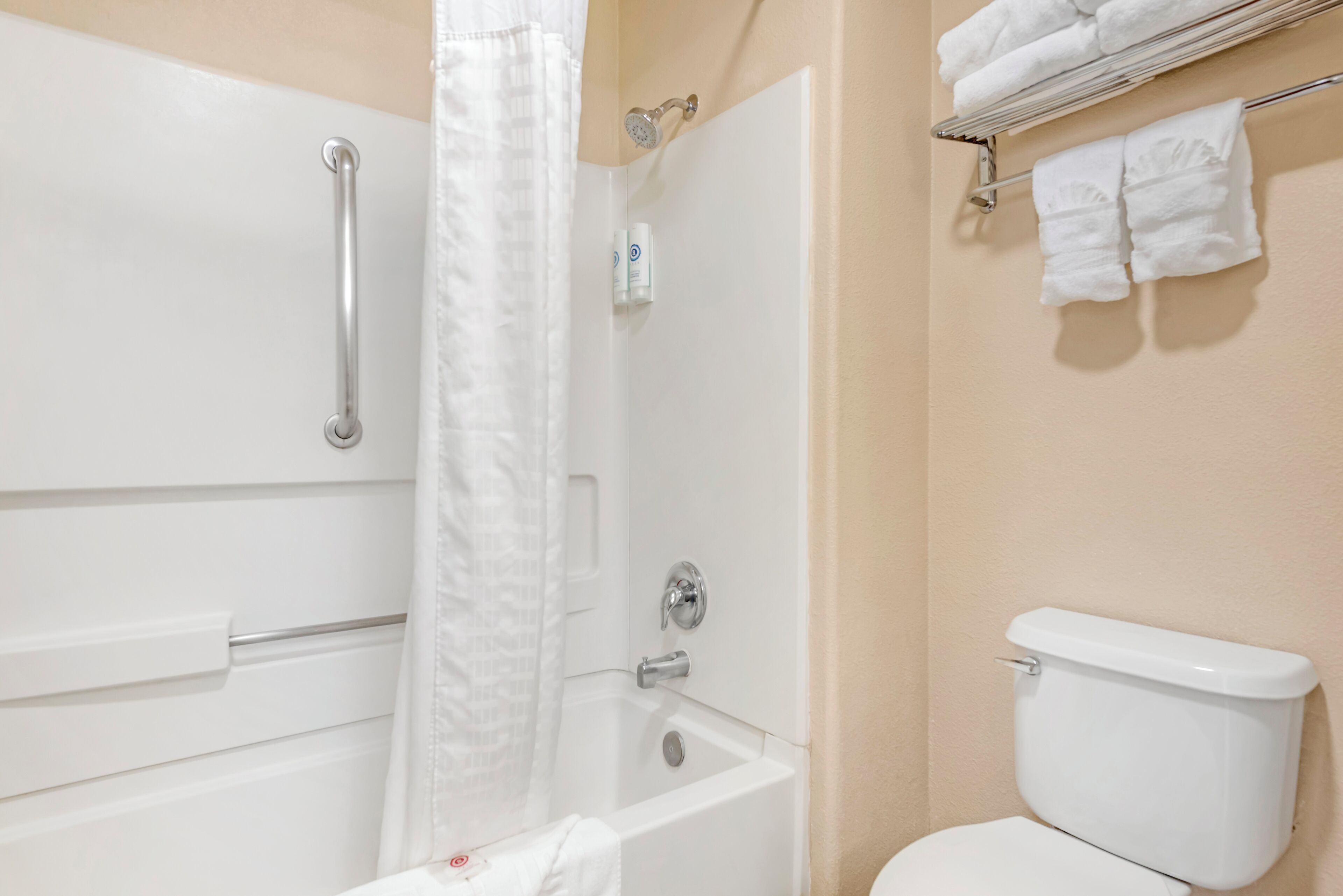 Et badeværelse med badekar, brusebad, toilet og et håndklædetørrestativ med håndklæder.