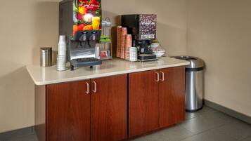 A coffee station with a coffee machine, a juice dispenser, and a trash can.