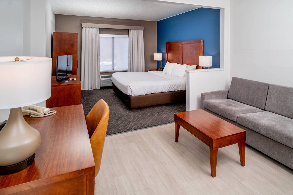Een hotelkamer met een bed, een bank, een bureau met lamp en een televisie.