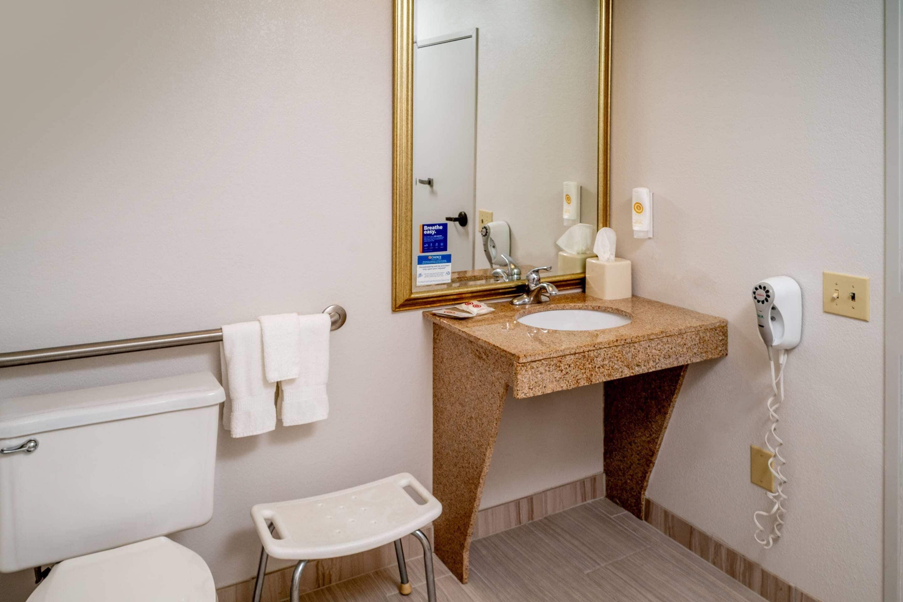 A bathroom with a toilet, sink, and a small stool.