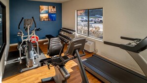 Una palestra con macchinari cardio, manubri e tapis roulant.