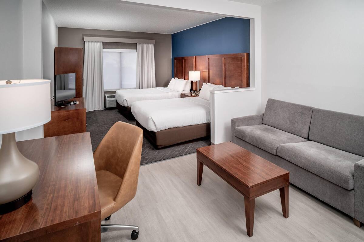 Een hotelkamer met twee bedden, een bank, een bureau met lamp en een televisie.