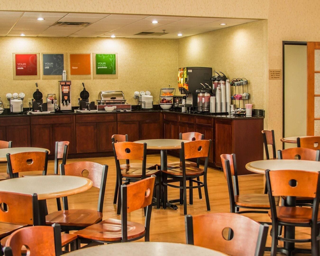 Un café avec des tables et des chaises en bois, un comptoir où l’on prépare différentes sortes de café, et des décorations murales.