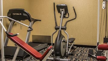 A hotel fitness room with a treadmill, elliptical, and weight bench.