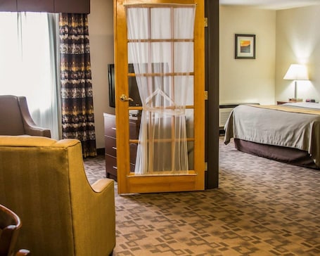 A hotel room with a bed, a chair, a desk, and a door with a curtain.. Comfort Inn Birch Run - Frankenmuth