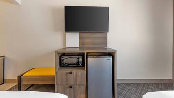 Una habitación de hotel con una cama, una mesita, un microondas y un refrigerador.