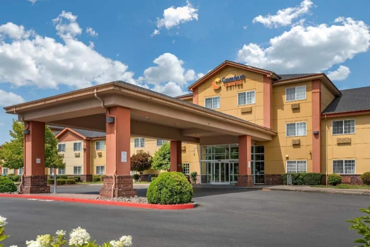 A Comfort Suites hotel with a covered entrance, multiple windows, and a clear sky.