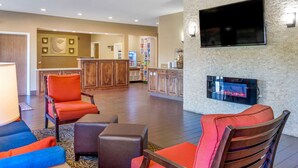 A hotel lobby with seating areas, a fireplace, a television, and a bar area.