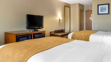 Una habitación de hotel con dos camas, televisión, escritorio y espejo.
