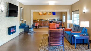 A spacious living area with a fireplace, comfortable seating, and a kitchen in the background.
