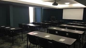 A conference room with tables and chairs, a projector, and a screen.