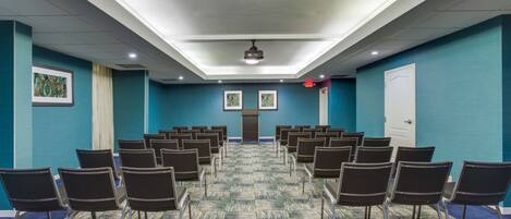 A conference room with rows of chairs, a projector, and a door.