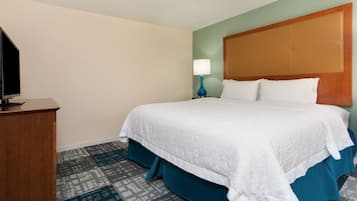 Una habitación de hotel con cama, escritorio, lámpara y televisión.
