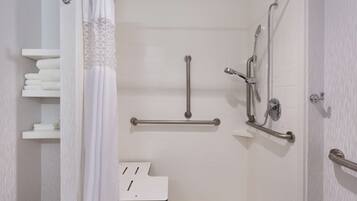 Un baño moderno con azulejos blancos, una ducha con barras de apoyo y un banco blanco.