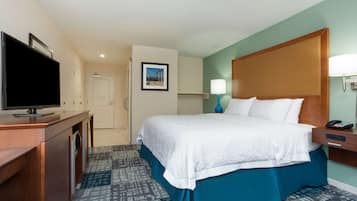 A hotel room with a bed, a television, a desk, and a nightstand.