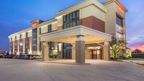 A Drury Inn & Suites hotel with a modern design, featuring a covered entrance and a parking lot with several cars. - Drury Inn & Suites Champaign (Champaign)