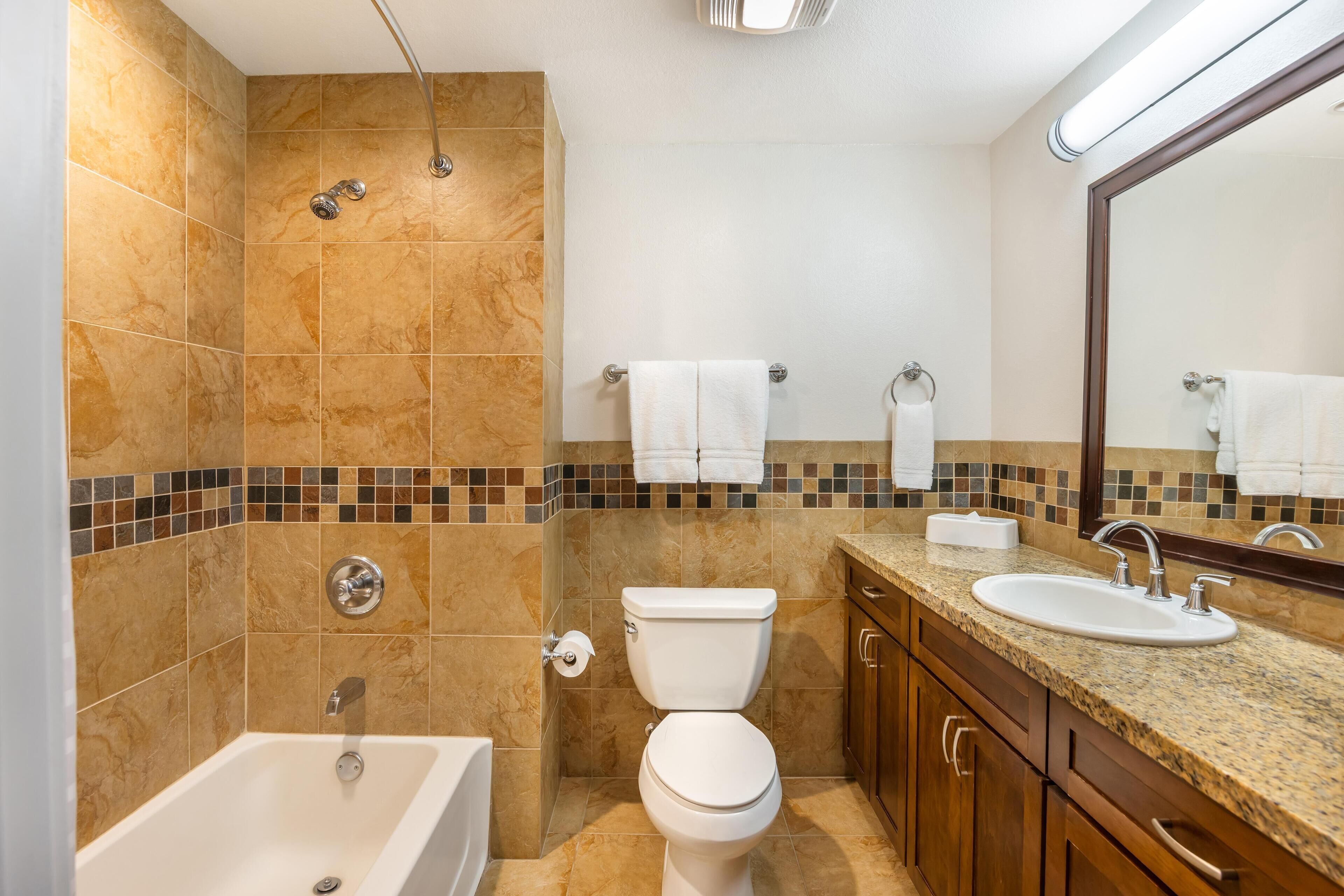 A bathroom with a bathtub, toilet, sink, and a shower area.