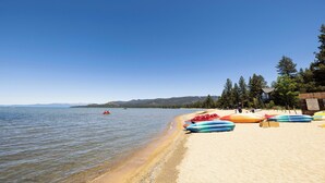 A beach with kayaks lined up on the sand, a clear sky, and a calm lake in the background. - Hilton Vacation Club Lake Tahoe Resort South (South Lake Tahoe)