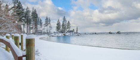 A snow-covered beach with wooden fences and trees in the background.