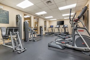 A gym with various exercise equipment including treadmills, elliptical machines, and weight machines.