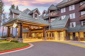 A multi-story hotel with a 'Welcome Home' sign, a covered entrance, and a stone facade.