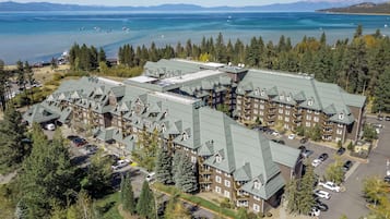 Un gran complejo hotelero con varias edificaciones, rodeado de un bosque denso y un lago con embarcaciones.