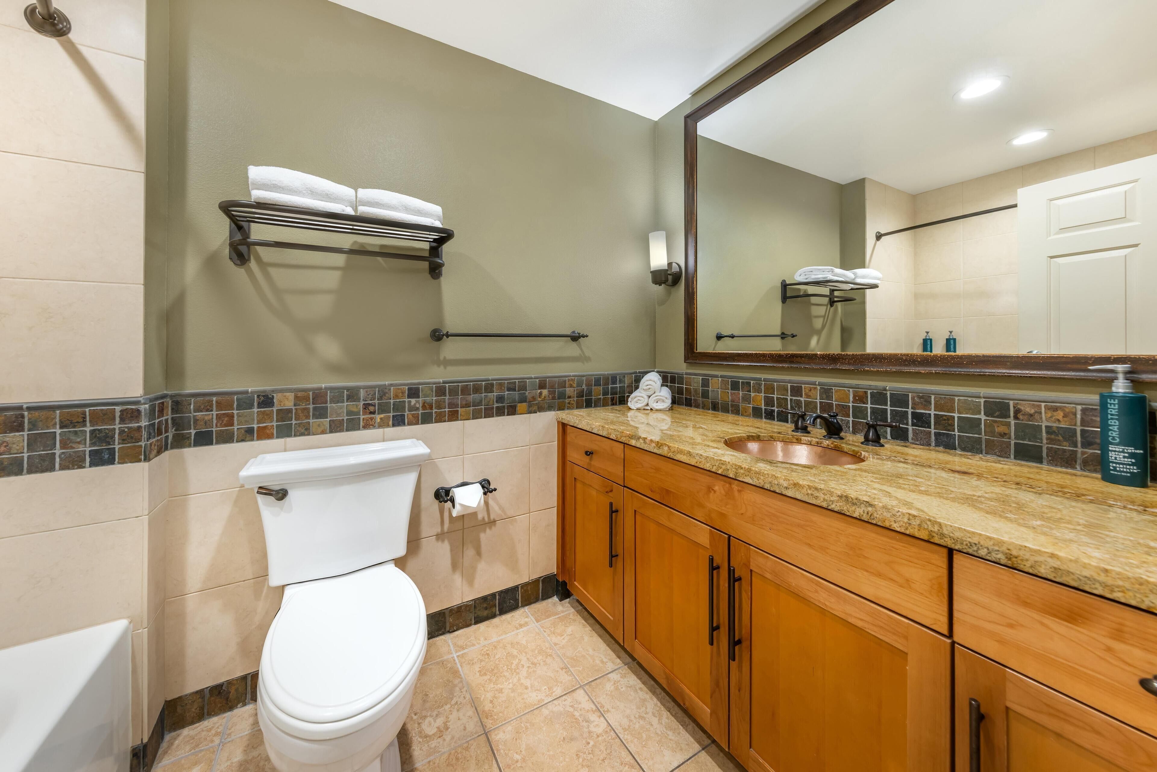 A bathroom with a toilet, sink, and wooden cabinets.