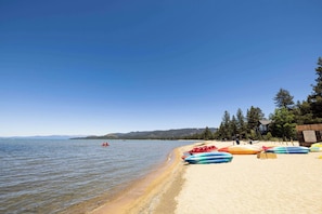 A beach with kayaks lined up on the sand, a clear sky, and a calm lake in the background. - Hilton Vacation Club Lake Tahoe Resort South (South Lake Tahoe)