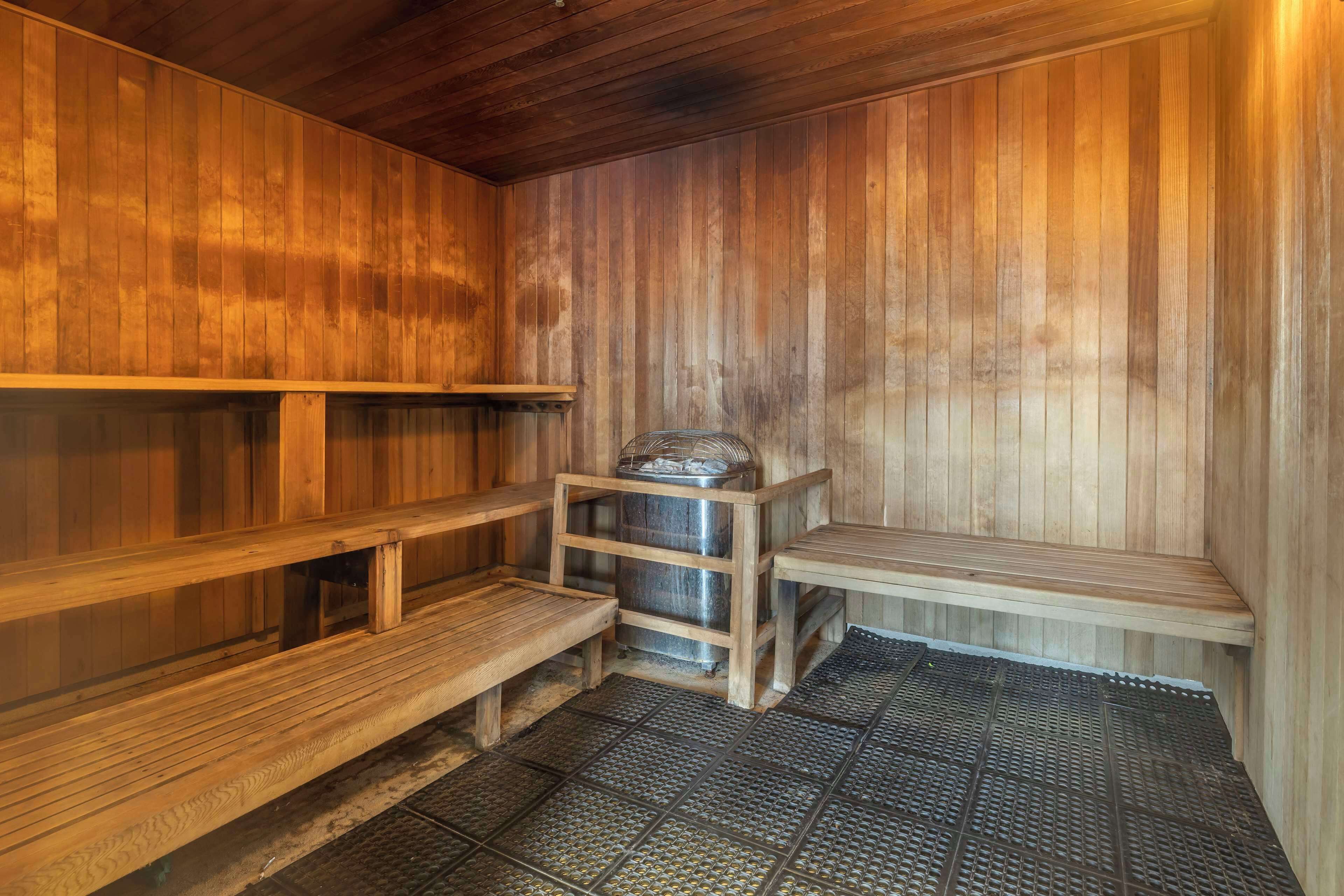 A sauna with wooden benches and a metal container.