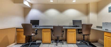 A conference room with four chairs, a long table, and a ceiling with recessed lighting.