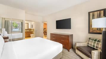 Una habitación de hotel con una cama grande, un sofá, un televisor y un escritorio.